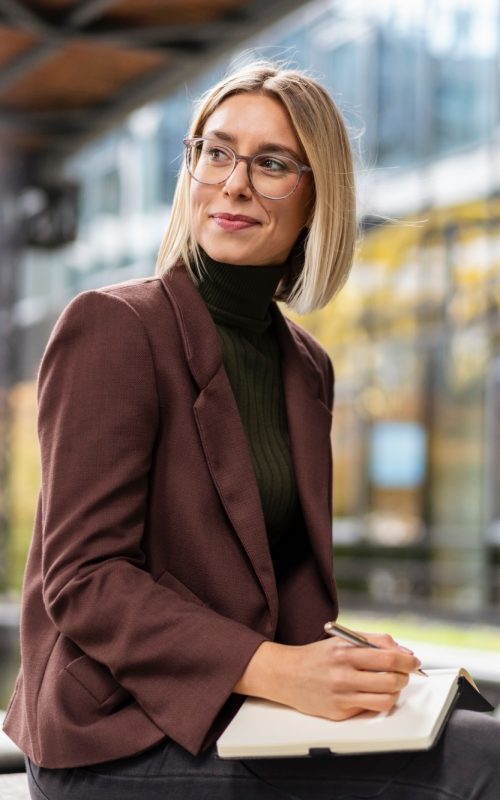 Smiling young businesswoman with notebook in the city
